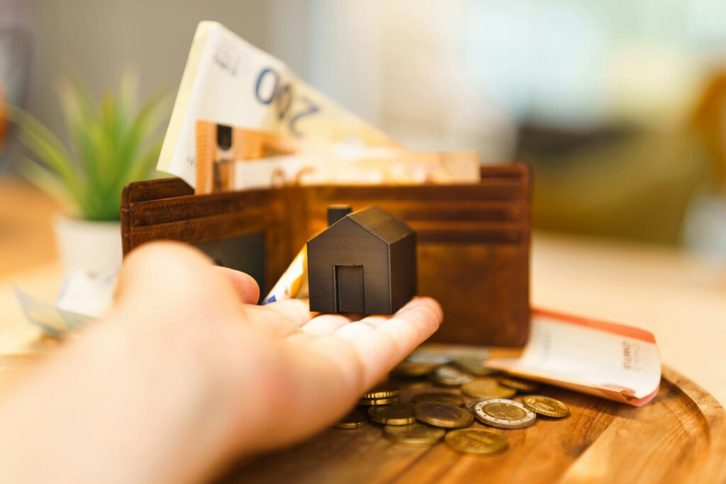 Hand holding house model with money