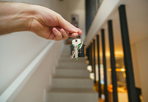 Hand holding keys near staircase